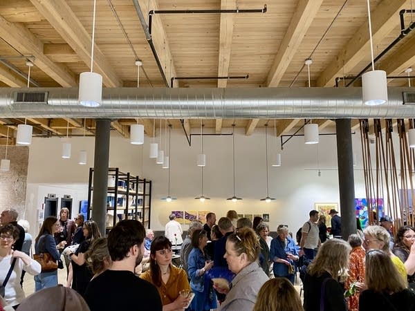 A group of people gather in an opening gallery.