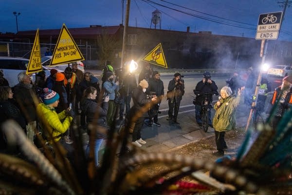 People listen to a woman speak at a protest