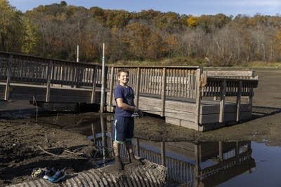 A boy fishes in a small pond next to a dock.