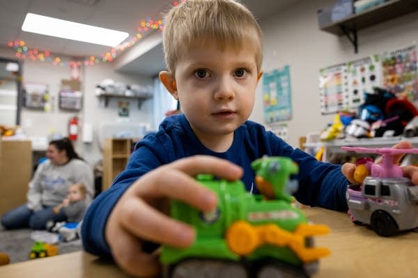 A boy plays with plastic toy vehicles