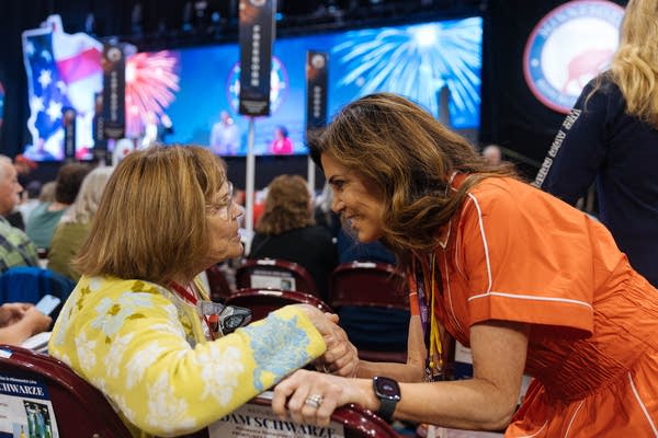 A woman shakes hands with people at the convention.