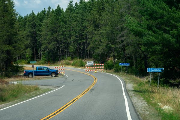 A Road Closed sign blocks a forest road.