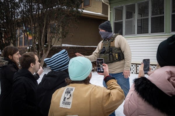 A federal agent speaks to neighbors outside a house