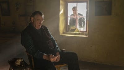 man sitting on a char and man behind a window