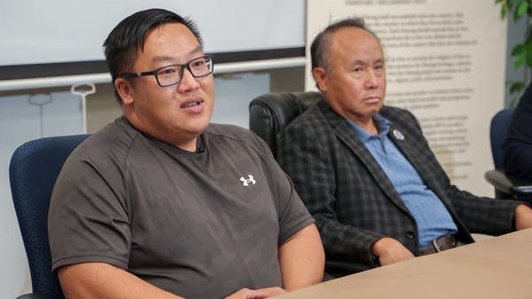 Two Hmong men sit at a table