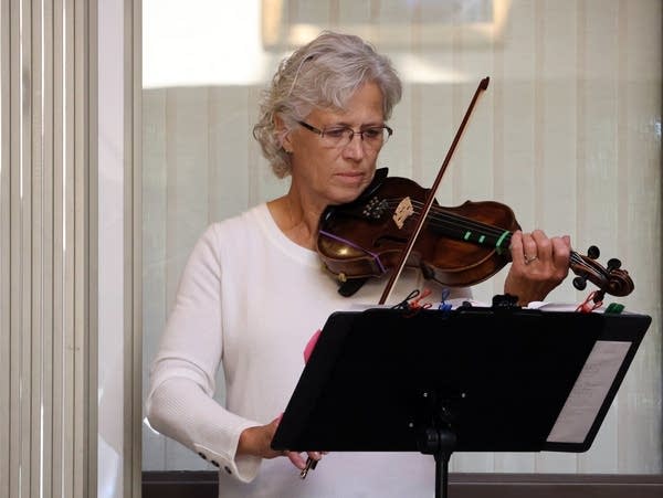 a woman dressed in white plays a violin