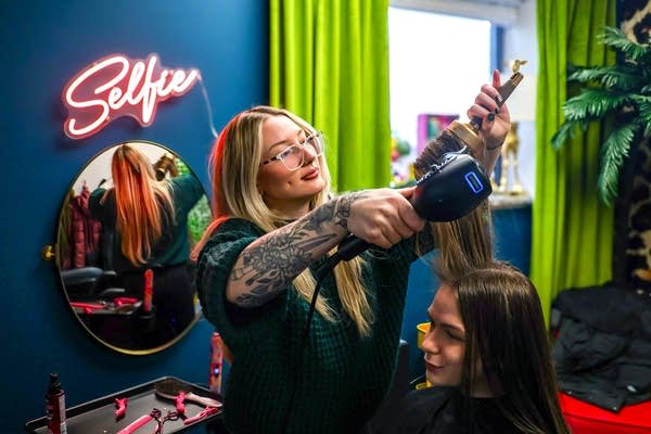 A stylist brushes and dries a client's hair.