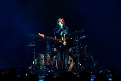 A musician sings and plays guitar onstage 