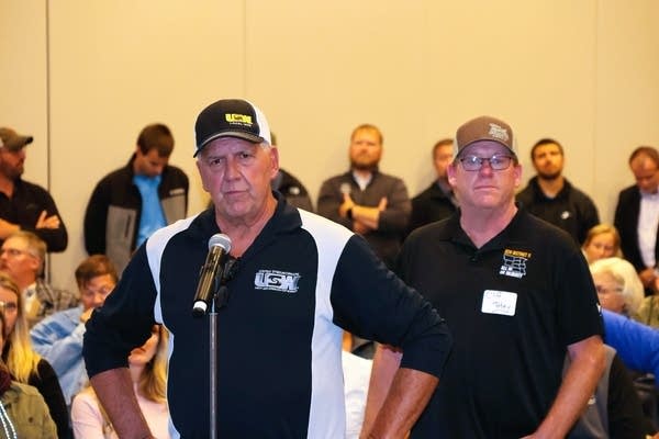 Two men talk to a room