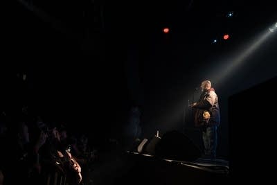 A rapper performs onstage during a show in a music venue