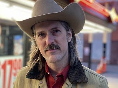 A man in a cowboy hat under bright lights at night
