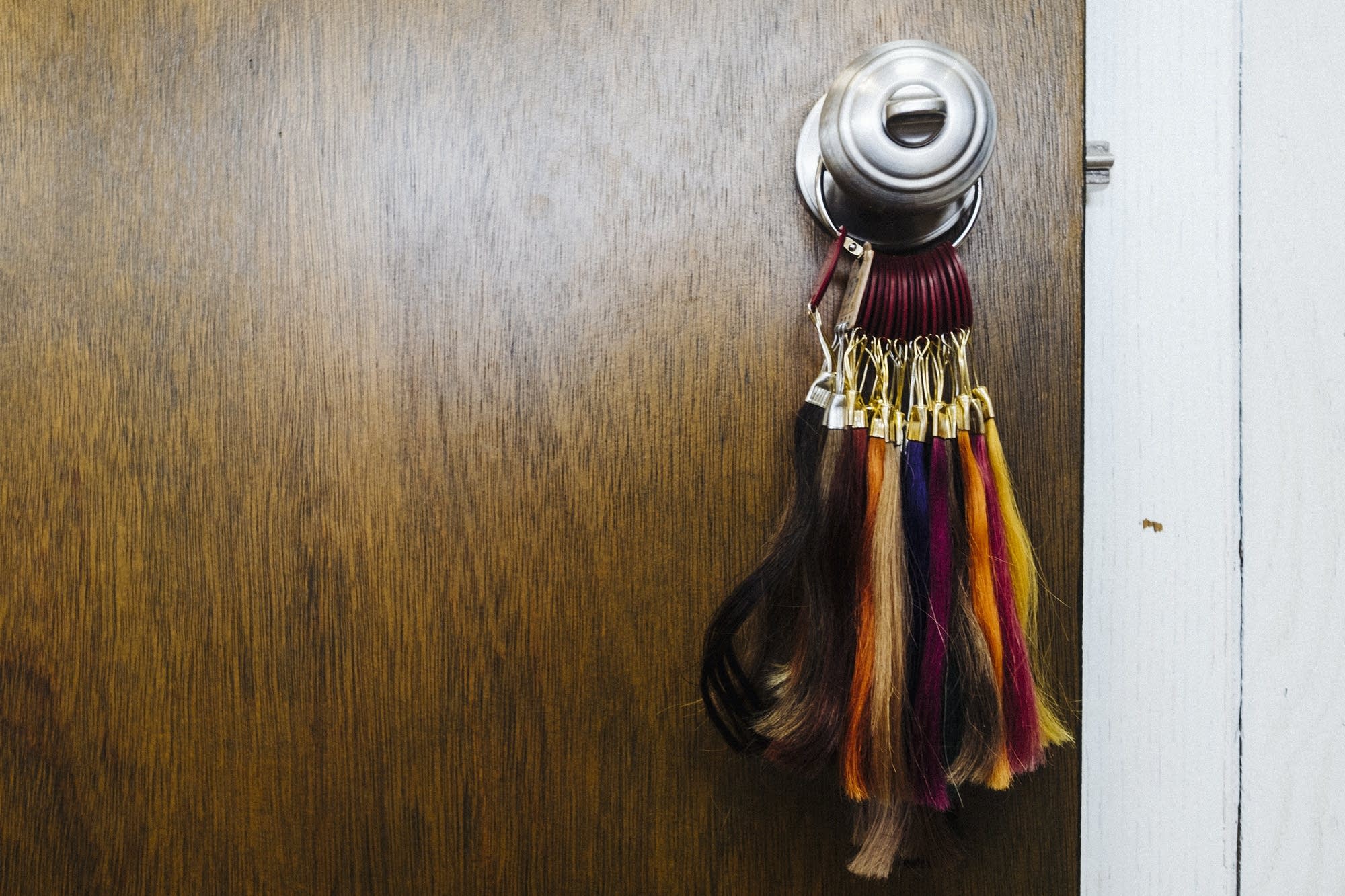 Colored hair swatches hang from a door knob.
