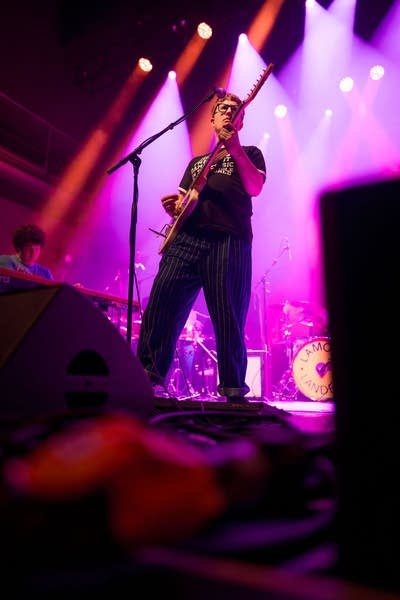 A musician sings and plays guitar in a large music venue