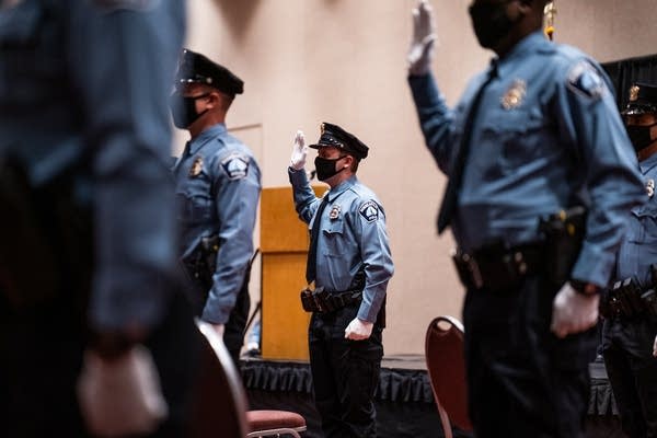 Police in uniform raise their right hands.