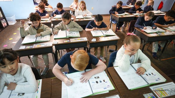 Children sit at desks in a classroom.