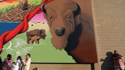 Peiple stand at the base of a mural