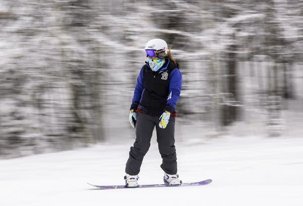 A person snow boards down a slope