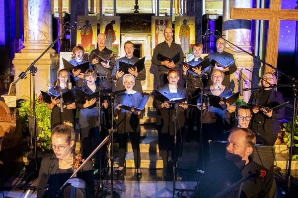 Performers sing in a brightly lit cathedral.