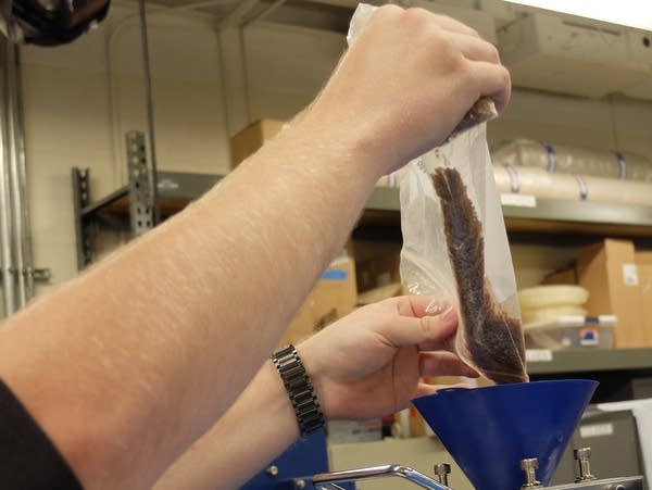 dumping a bag of pellets into a machine