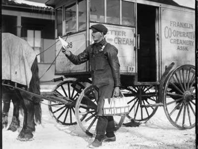 A man delivers bottles of milk by horse-drawn carriage.