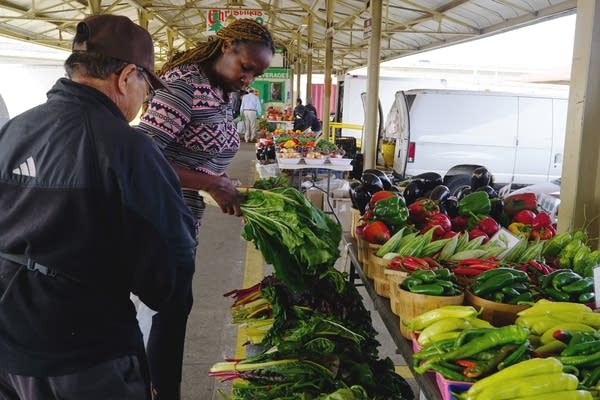 Two people look over a display of vegetables.