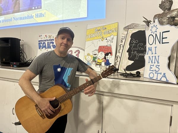 A man posing for photo holding a guitar 