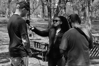 Two radio journalists interviewing a man in a park