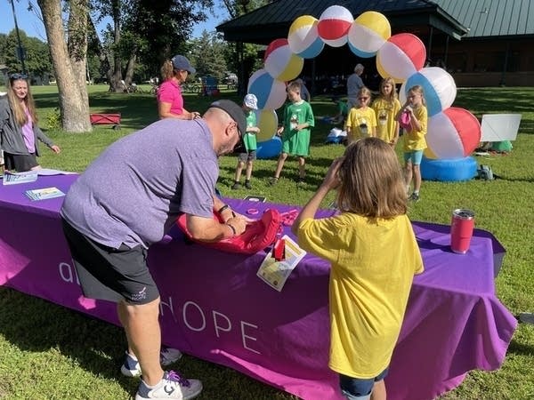 A man leans down to write on a life jacket.