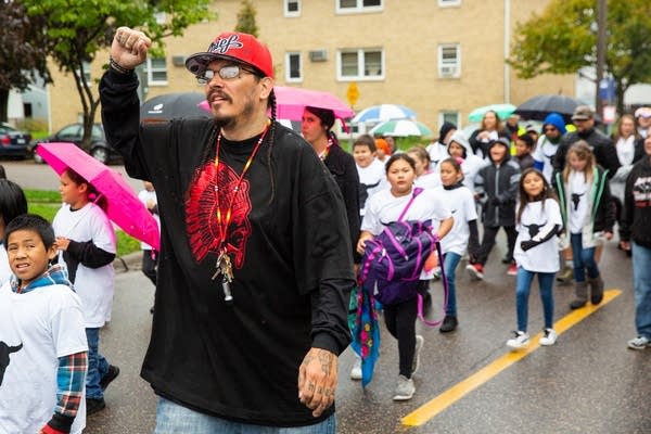 Mike Eagle Tail marches alongside children.