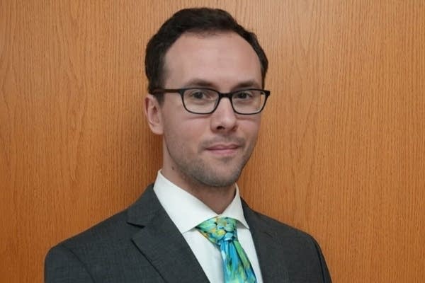 A man poses for a photo in a suit and tie.