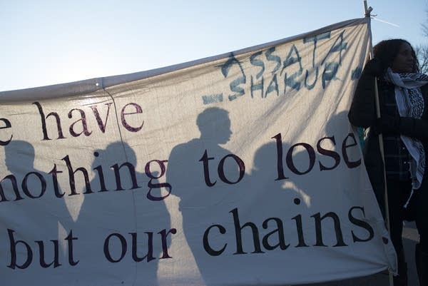 Protestors are silhouetted against a banner.