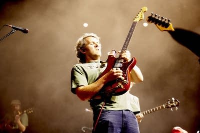 A guitarist performing onstage in a large music venue