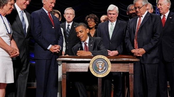 U.S. President Barack Obama (C) signs the the financial reform bill into law during a ceremony with (L-R) Robin Fox, Andrew Giordano, Vice President Joe Biden, Senate Majority Leader Harry Reid (D-Nev.), Rep. Maxine Waters (D-Calif.), Senate Banking Committee Chairman Christopher Dodd (D-Conn.), House Financial Services Committee Chairman Barney Frank (D-Mass.) and House Majority Leader Steny Hoyer (D-Md.) at the Ronald Reagan Building and International Trade Center July 21, 2010 in Washington, D.C.