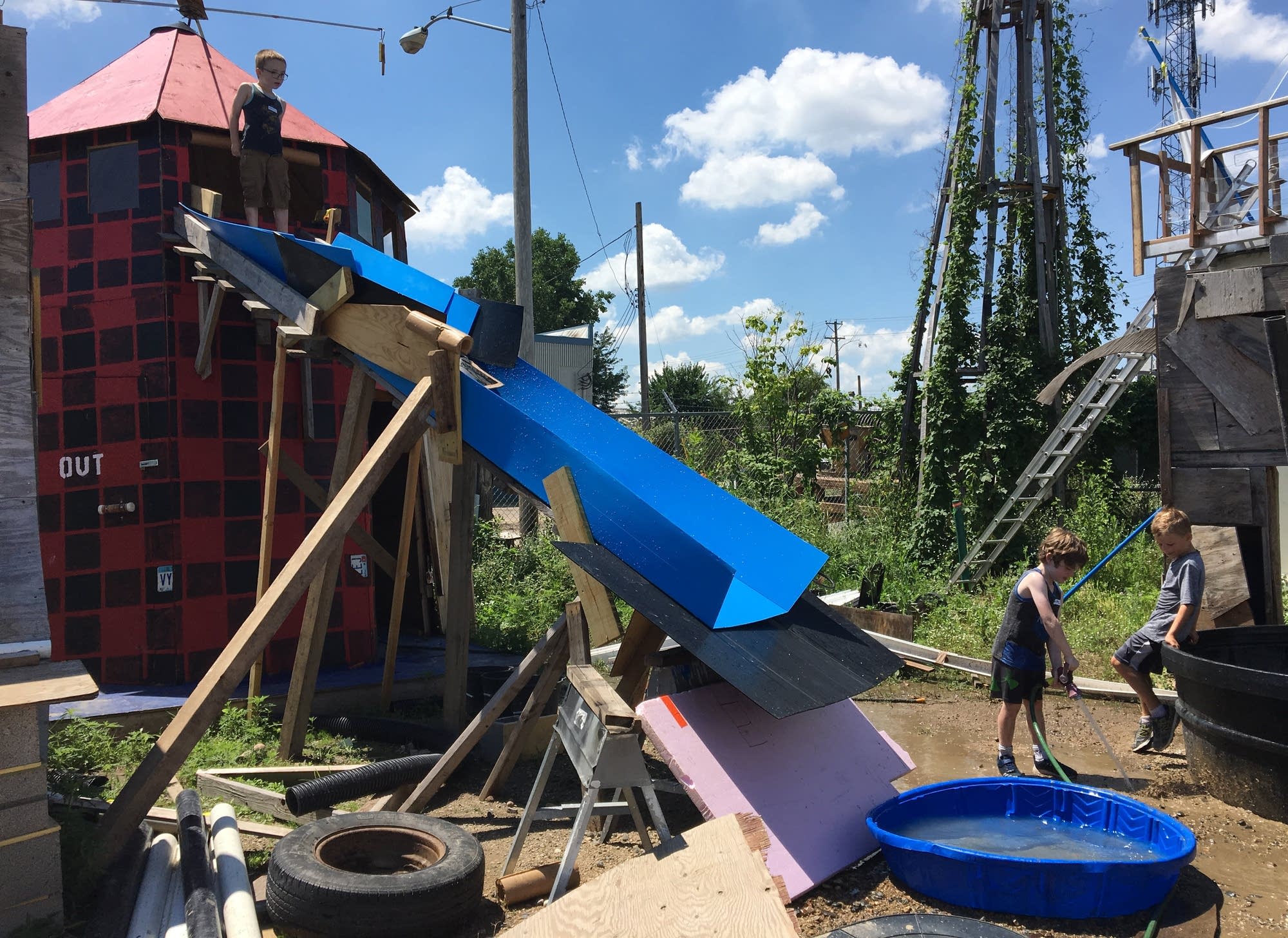 Wolf Attridge stands at the top of the water slide of recycled materials.