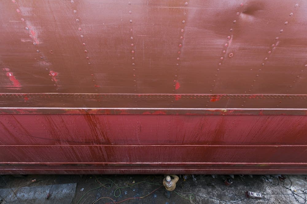 A worker performs maintenance on the hull.