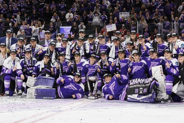 Frost hockey players gather near the Walter Cup for a photo.