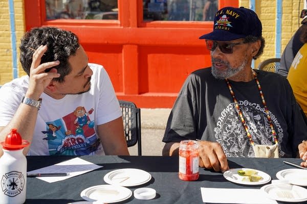Two men talk at a table