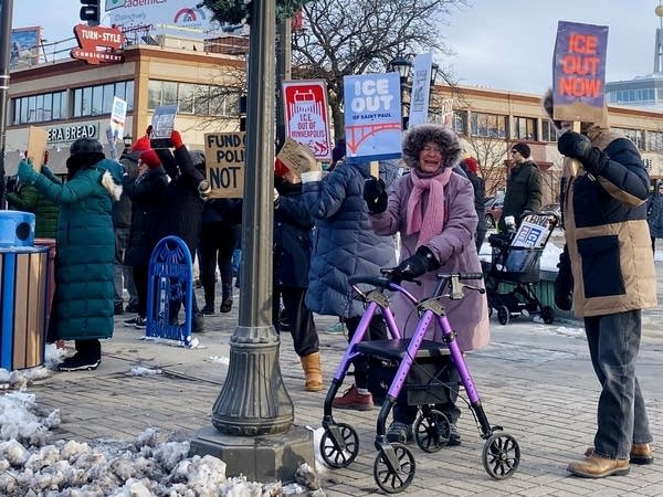 A large group of protesters hold signs up.