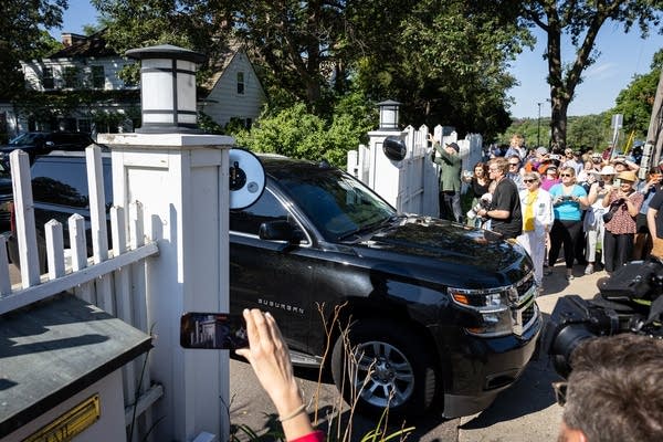 People cheer as a black SUV drives past