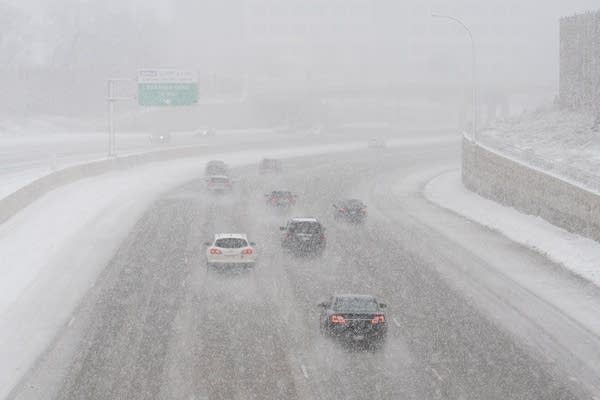 Cars drive through a heavy snowstorm on the interstate.