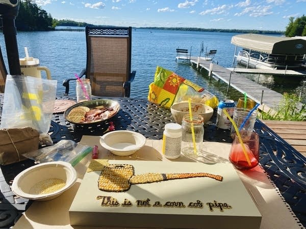 An in-progress work of crop art lays on a table overlooking a lake on a sunny day.