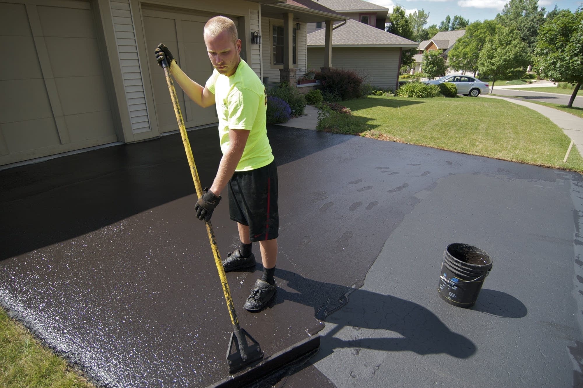 A coal tar-based sealant is applied on a driveway.