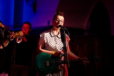 a woman singing and playing guitar on stage