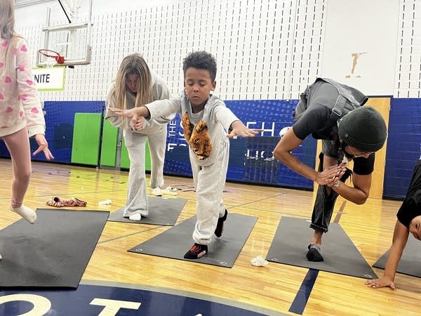 Kids lean forward and balance while on yoga mats.