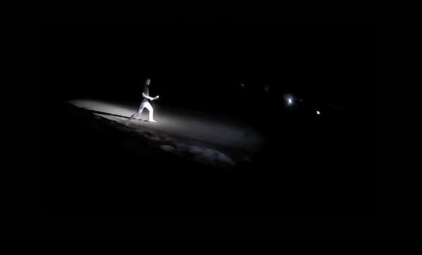 A person spotlighted by a flashlight while running at night