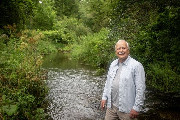 A man stands by a creek