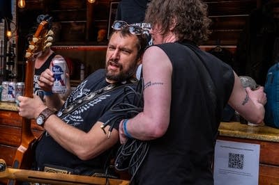 Man holding guitar leaning on man