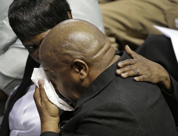 A mourner is comforted during a memorial service.