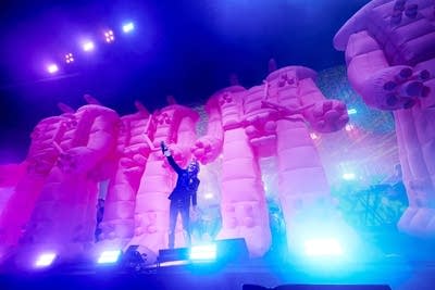 A musician sings while four massive, inflatable robots stand upstage