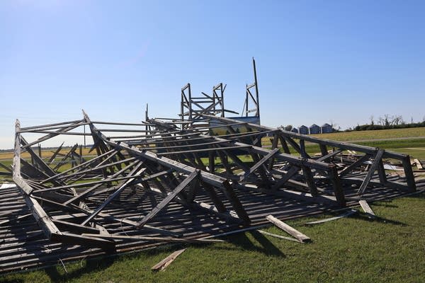 A flattened drive-in theater screen lays on the ground under a pile of wooden wreckage.